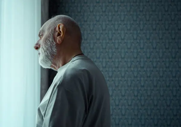 An older man at the window, reflecting quietly
