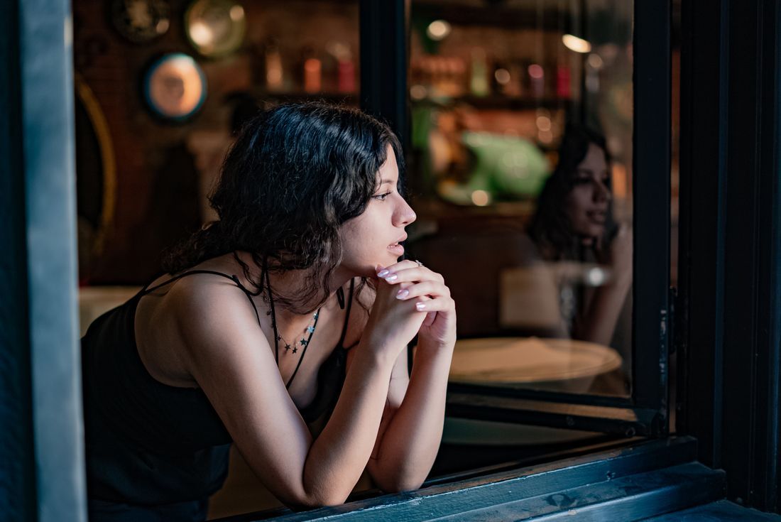 A woman sitting thoughtfully by a window at night