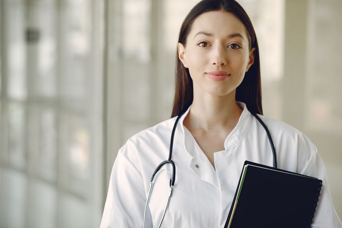 A doctor in a white coat with a stethoscope, holding a notebook