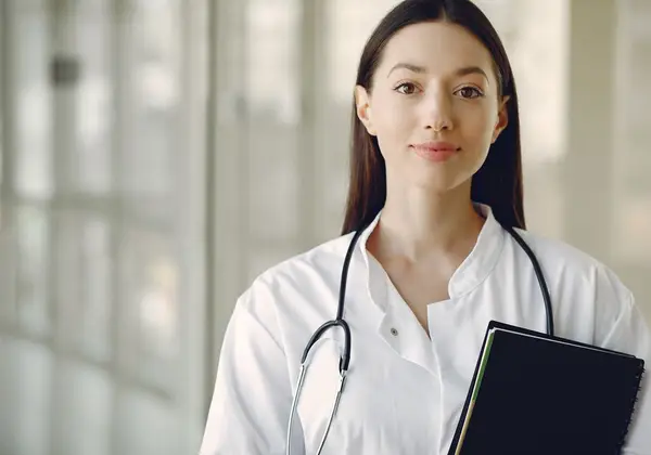 A doctor in a white coat with a stethoscope, holding a notebook