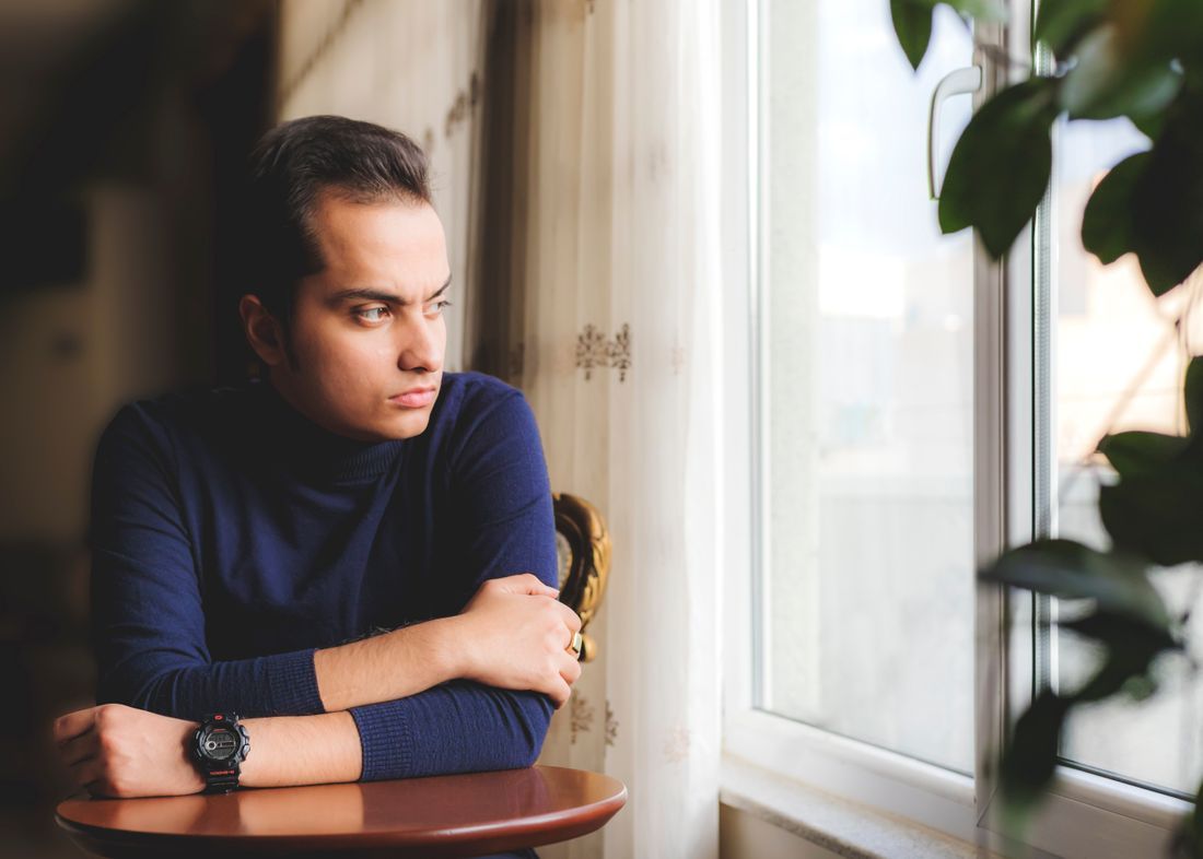 A young man sitting quietly by a window