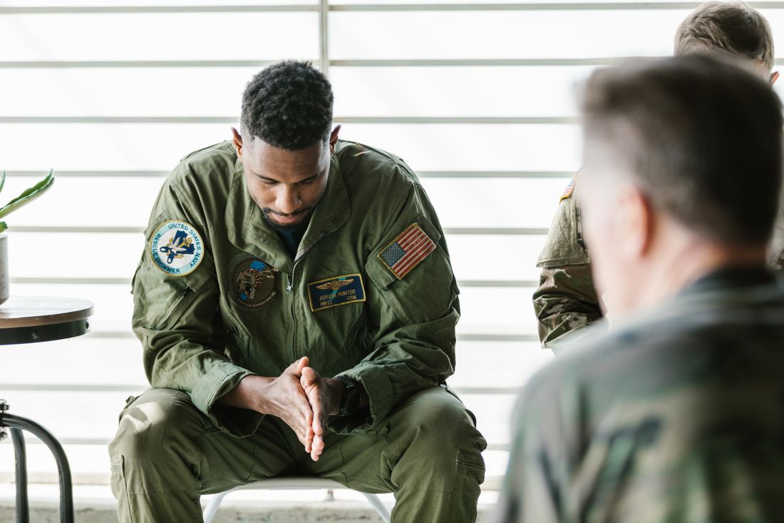 A service member sitting with head bowed in a quiet moment