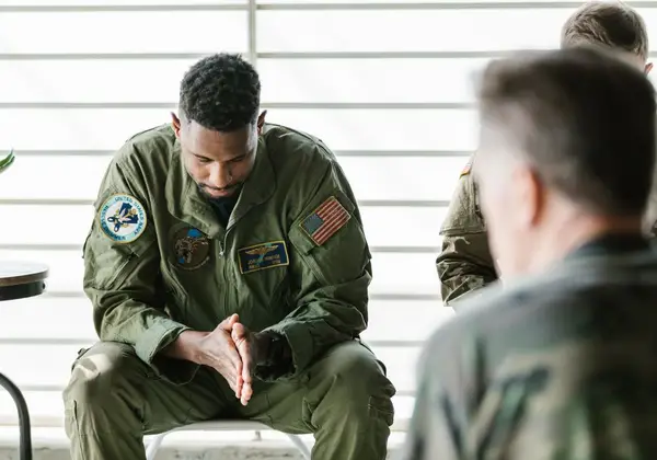 A service member sitting with head bowed in a quiet moment