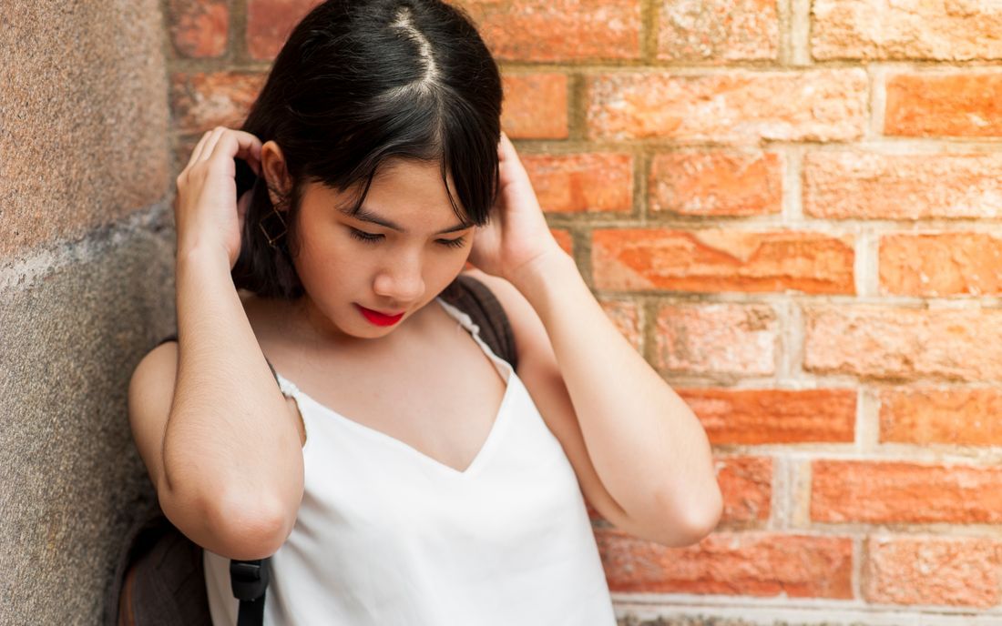 A teenage girl leaning against a wall, looking down