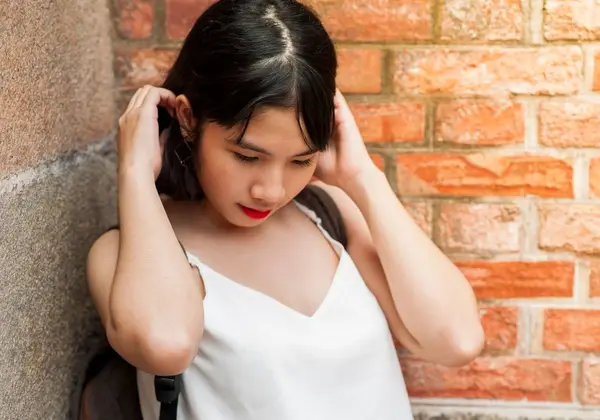 A teenage girl leaning against a wall, looking down