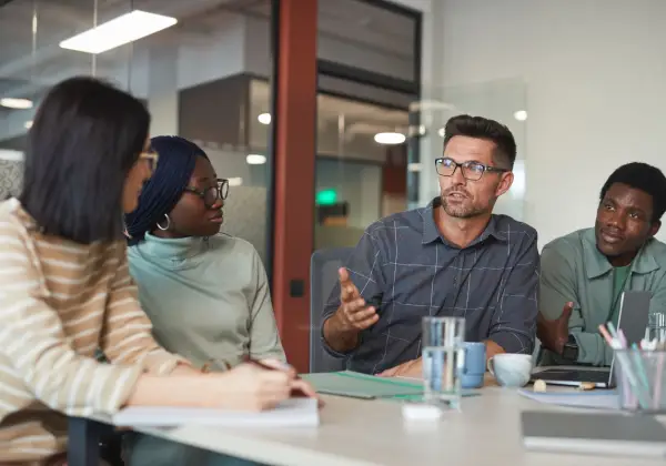 A leader listening and speaking with an engaged, diverse team
