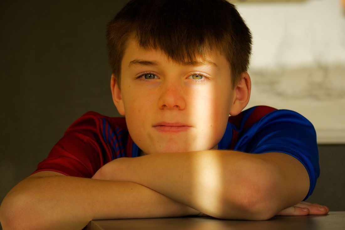 A thoughtful boy resting his chin on his arms in warm light