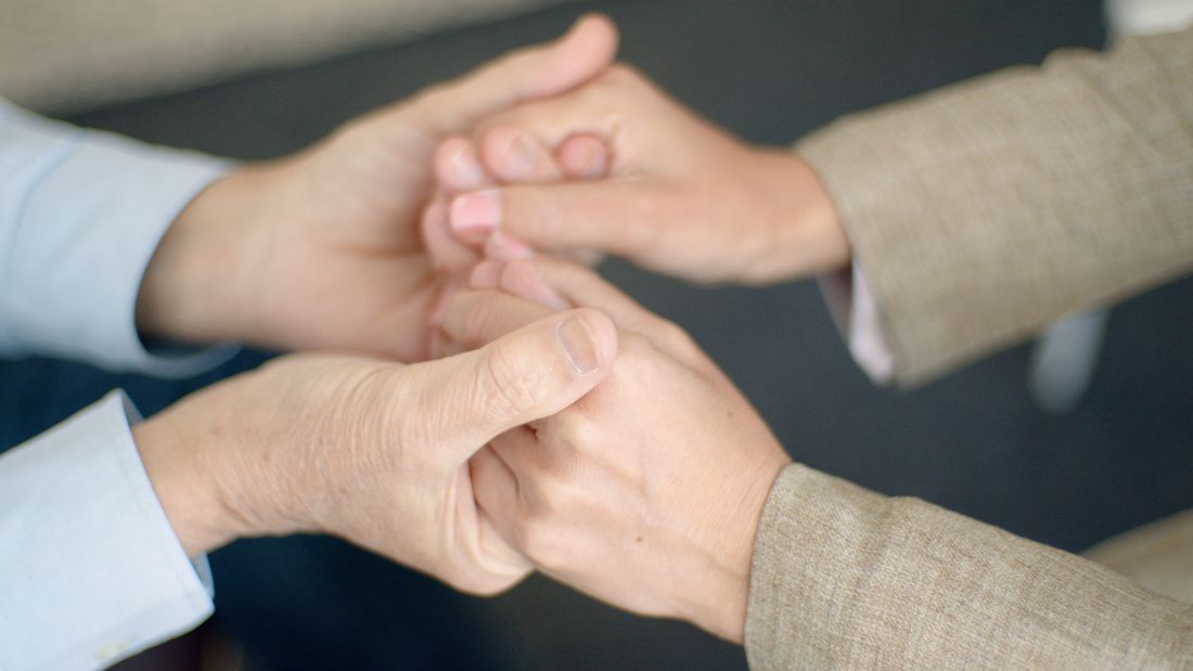 Two pairs of hands clasped together in support