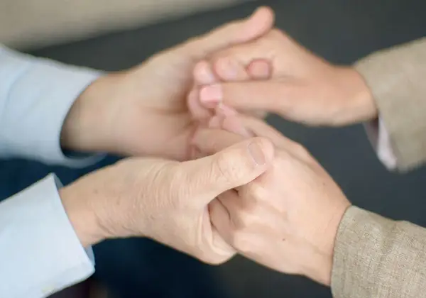 Two pairs of hands clasped together in support