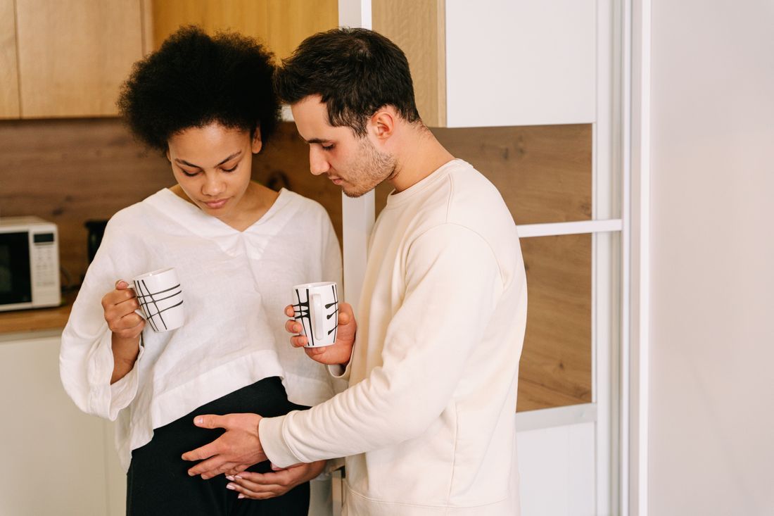 An expecting couple resting hands on the baby to come