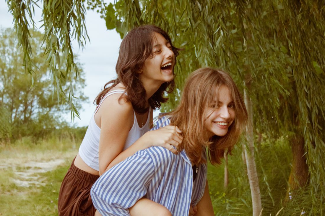 Two teen girls laughing together outdoors