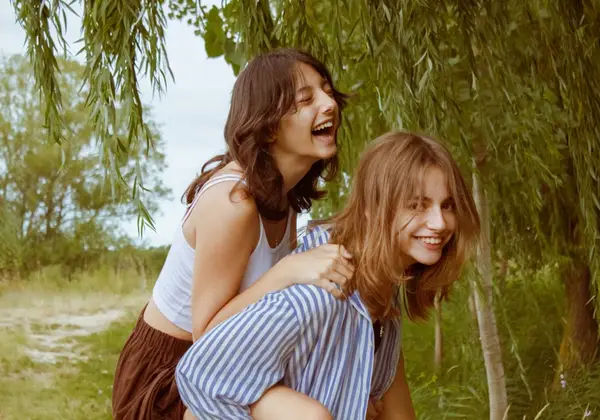 Two teen girls laughing together outdoors