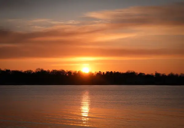 The sun setting warmly over calm water