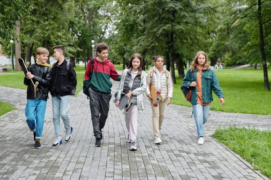 A group of middle schoolers walking together through a park