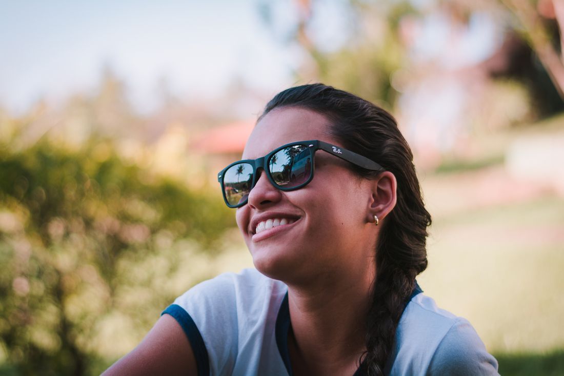 A woman smiling into the sunlight outdoors