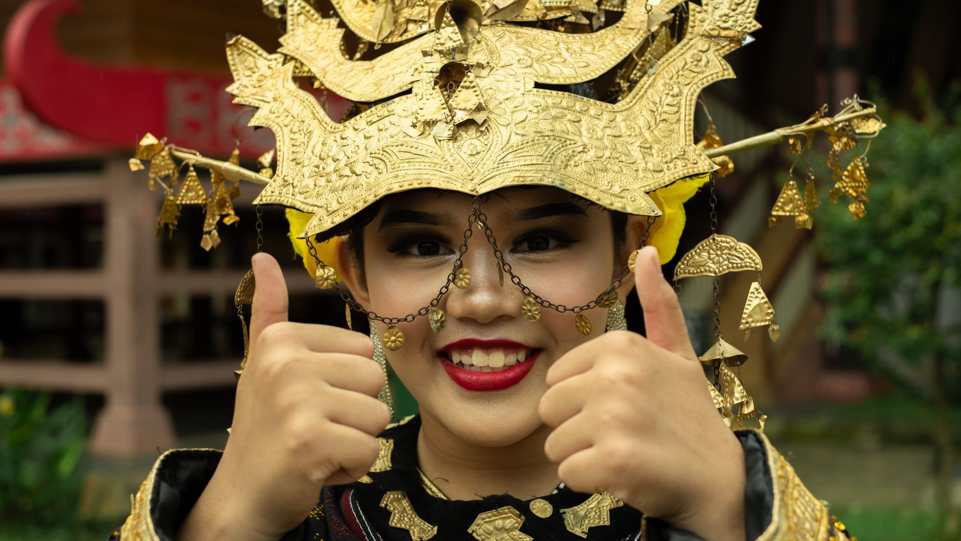 A smiling young Indonesian woman in golden ceremonial dress