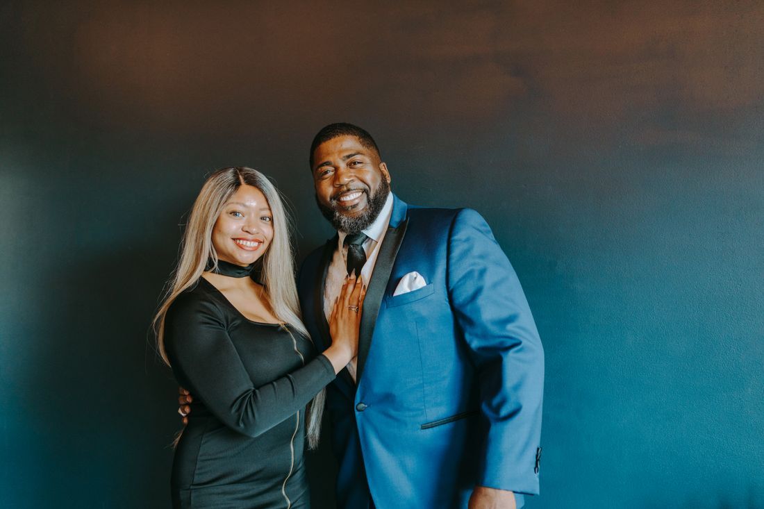A husband and wife dressed up, smiling together