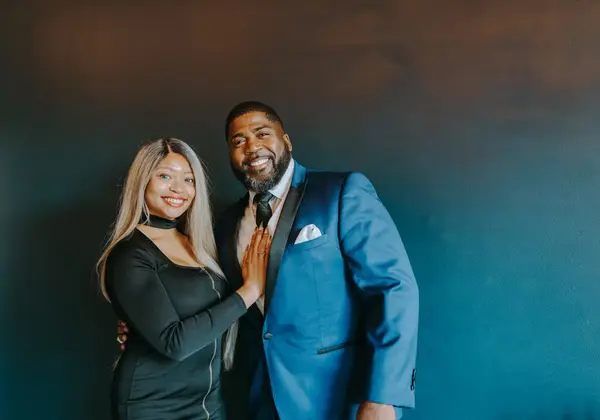 A husband and wife dressed up, smiling together