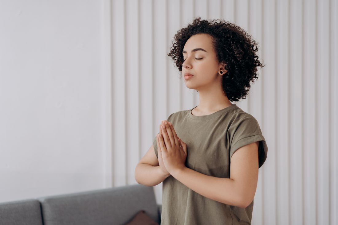 A woman in stillness, hands together in meditation