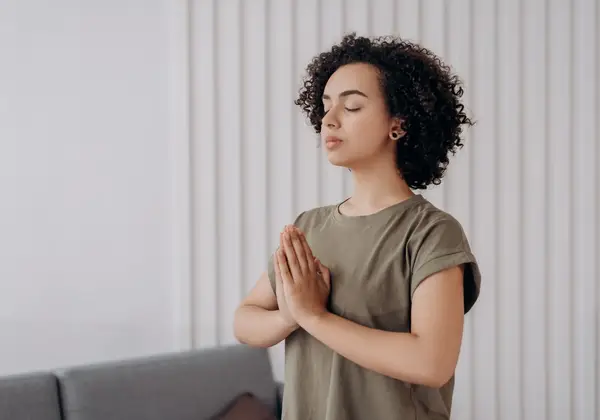 A woman in stillness, hands together in meditation