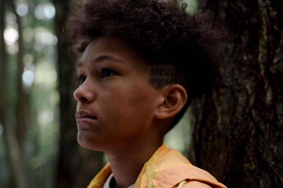 Close-up of a teenage boy looking up, hopeful, in the woods