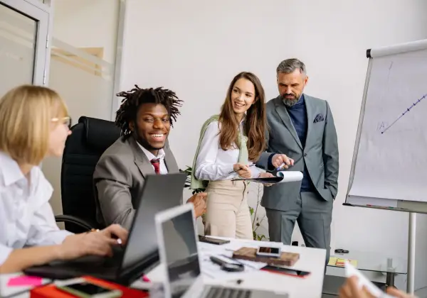 A mentor guiding a diverse team at a whiteboard