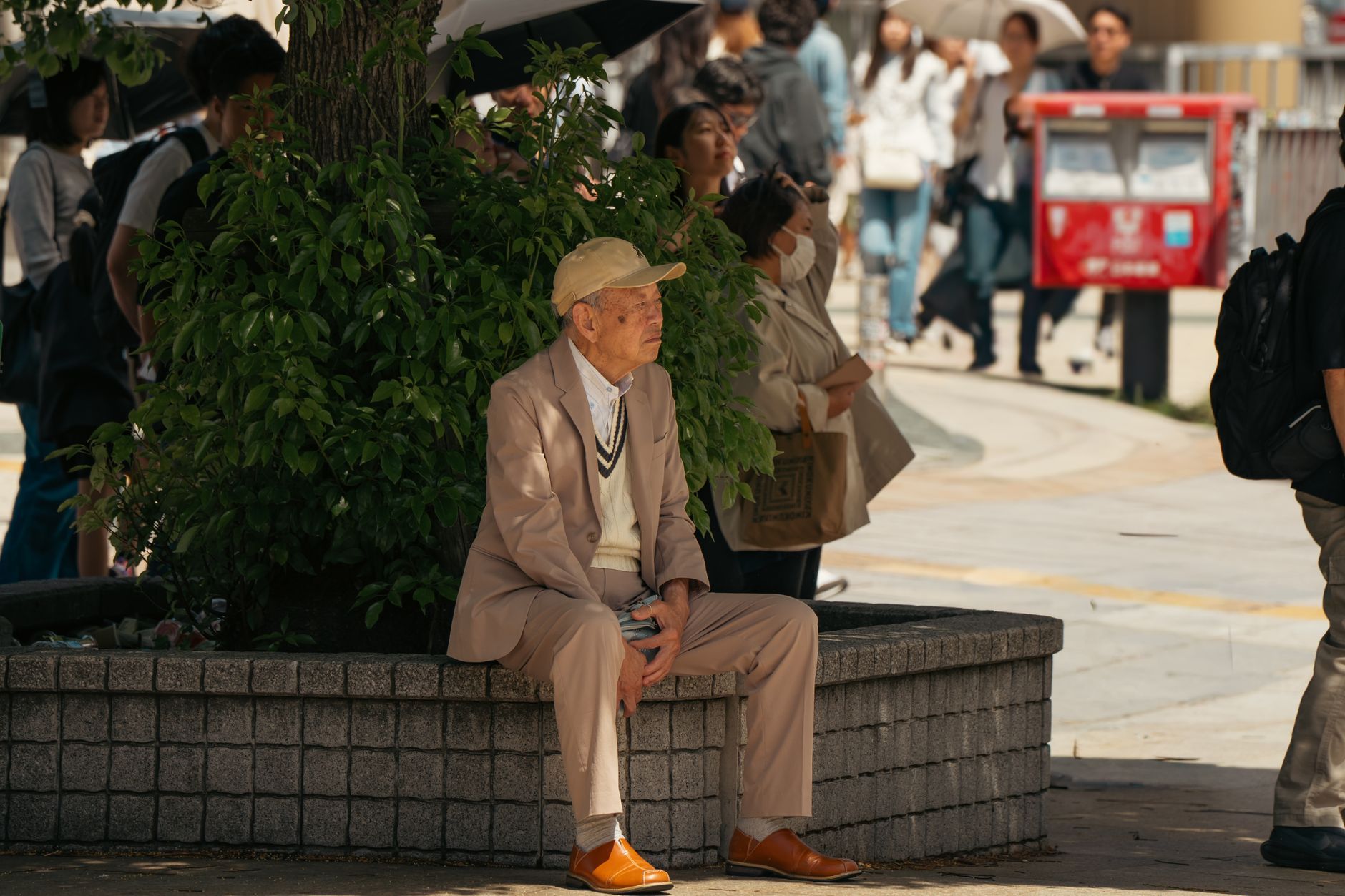 An elderly Japanese man resting on a city street