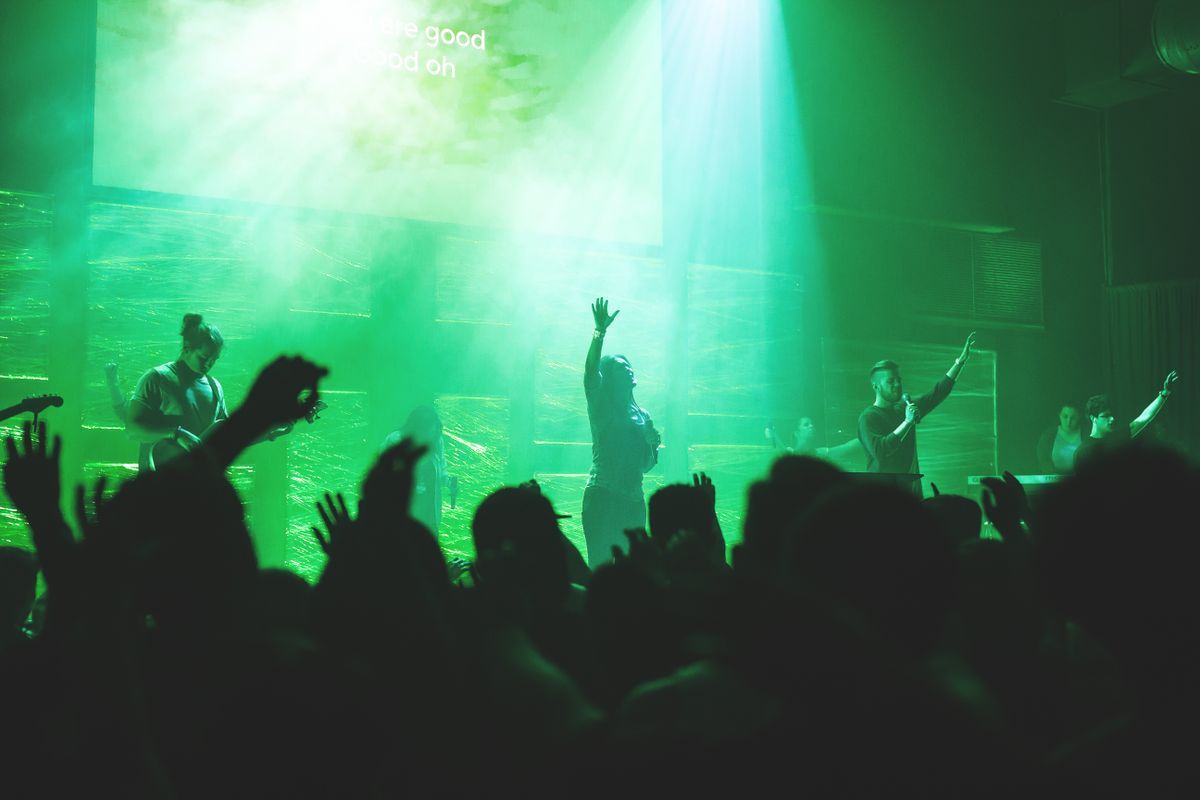 A worship band leading a congregation in song under stage lights