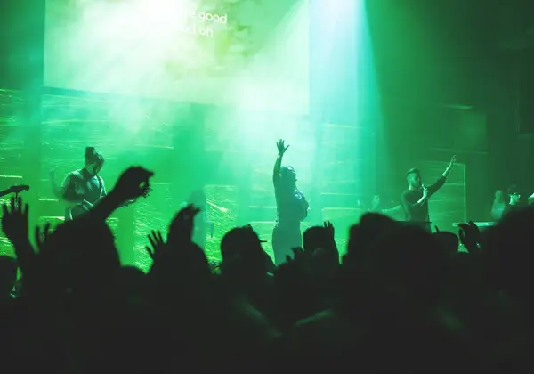 A worship band leading a congregation in song under stage lights