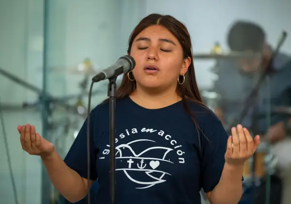 A young woman singing with eyes closed at a microphone during a church service
