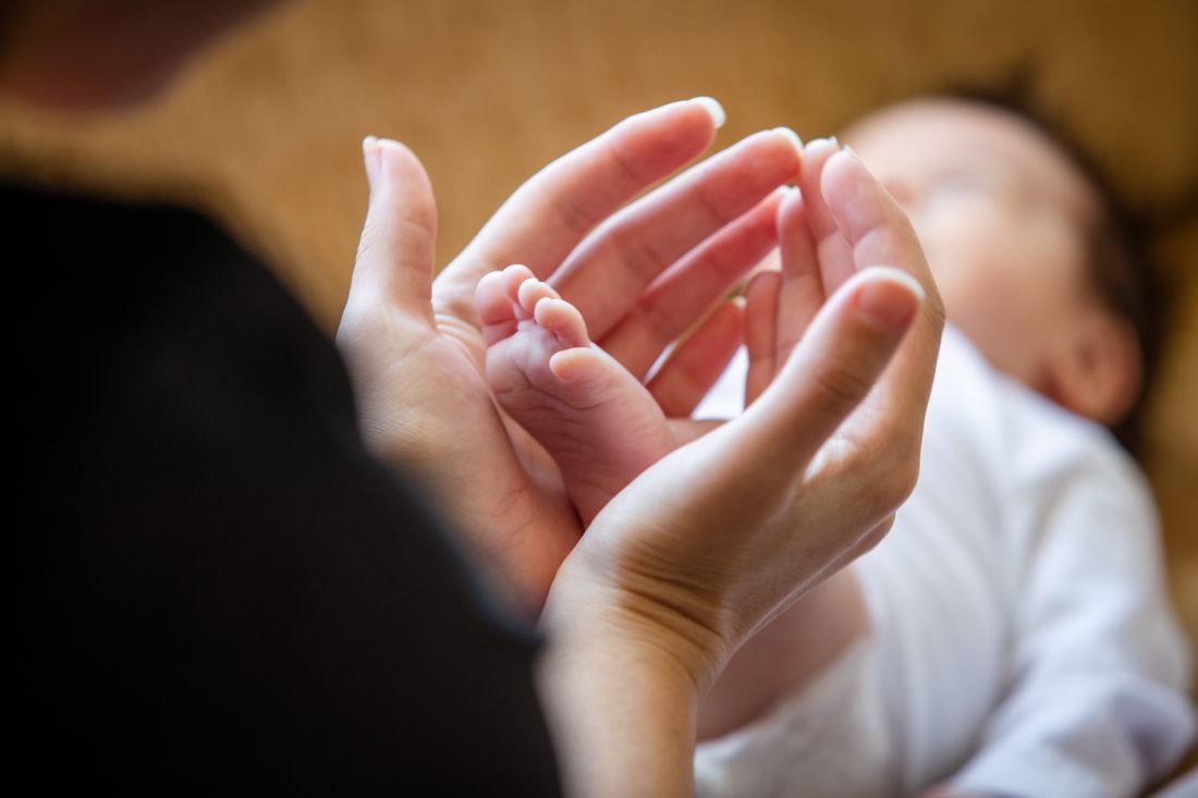 A newborn’s tiny foot cradled in a parent’s hands