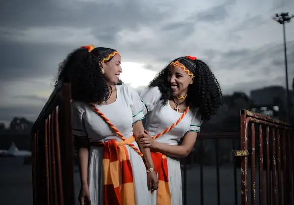 Two Ethiopian women in traditional dress, laughing together