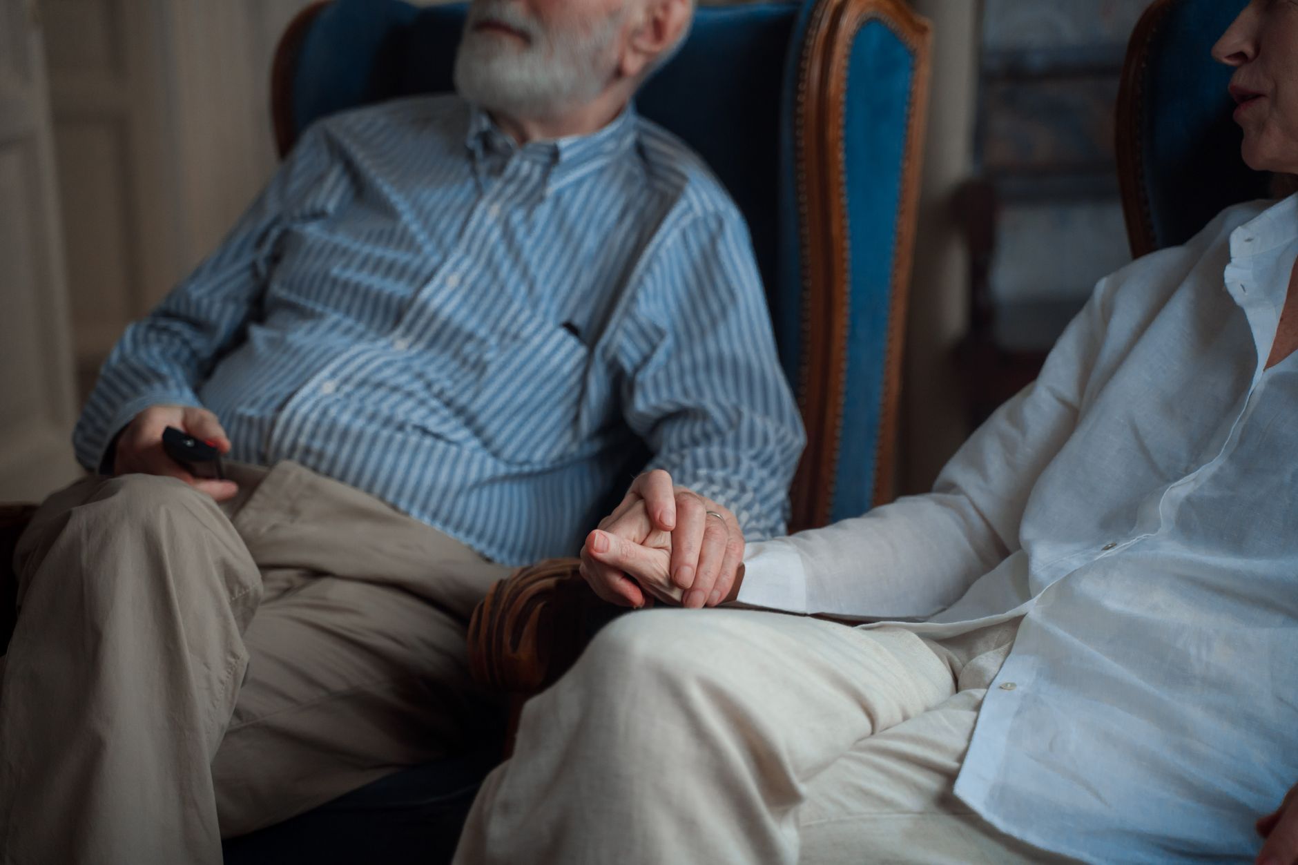 An older couple holding hands, their wedding rings visible