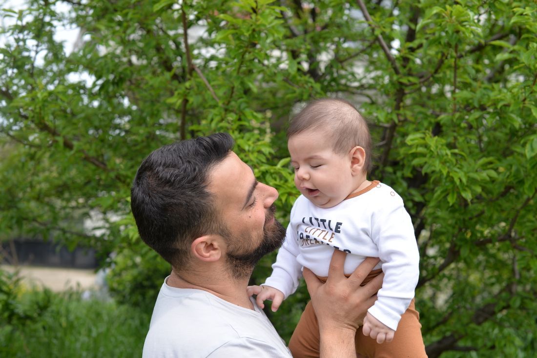 A father holding his baby close, face to face, outdoors