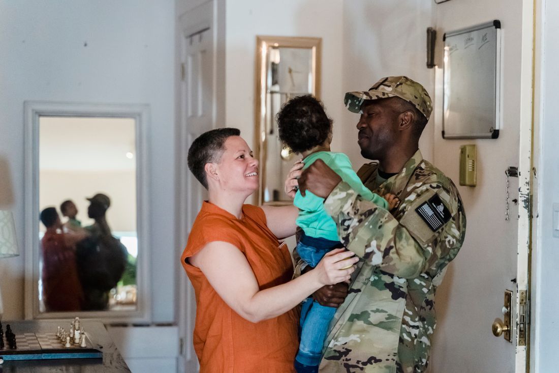 A soldier home from deployment, holding his child close to his wife