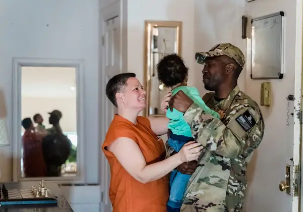 A soldier home from deployment, holding his child close to his wife