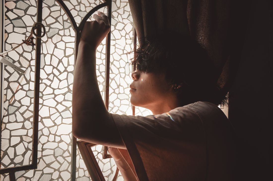 A young man by a window, light falling across him