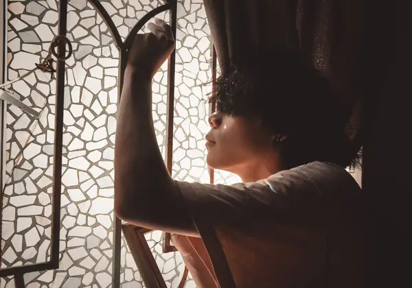 A young man by a window, light falling across him