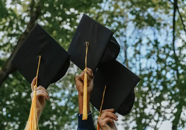 Graduation caps lifted against the sky