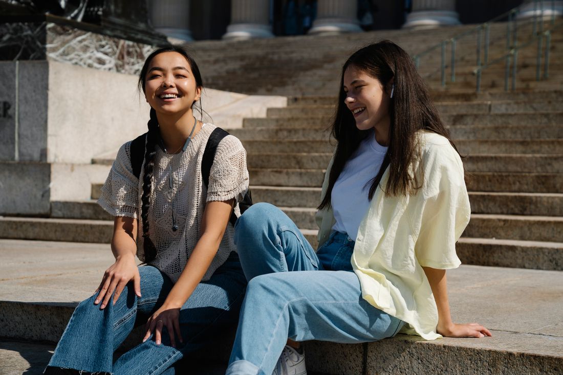 Two teenage girls laughing together on the steps