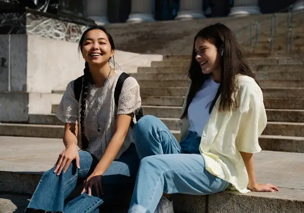 Two teenage girls laughing together on the steps