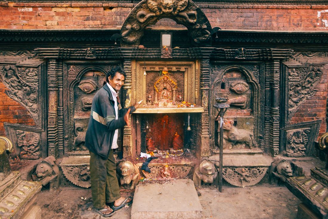 A man at a roadside shrine in everyday devotion