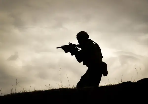 The silhouette of a soldier against a darkening sky