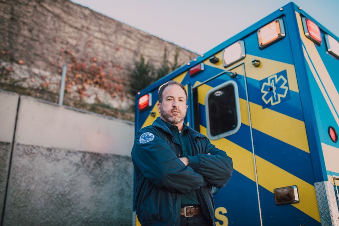 A paramedic standing with arms crossed by the ambulance