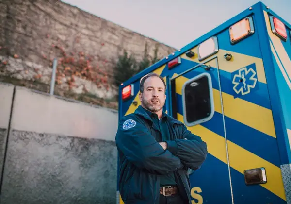 A paramedic standing with arms crossed by the ambulance