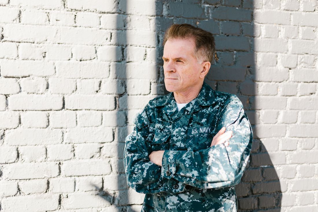 A Navy veteran leaning against a wall, lost in thought