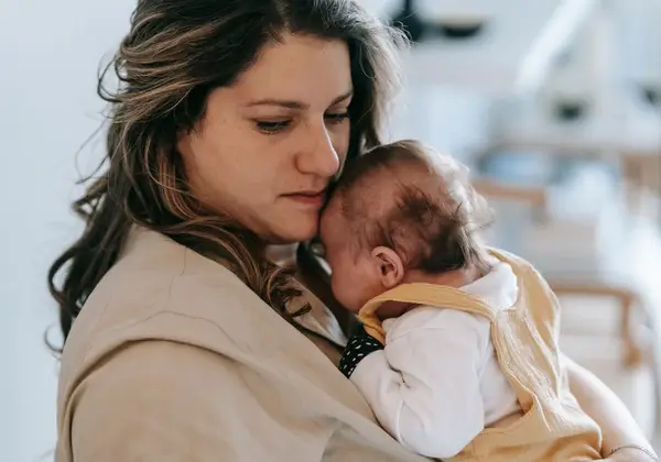 A mother resting her cheek against her newborn