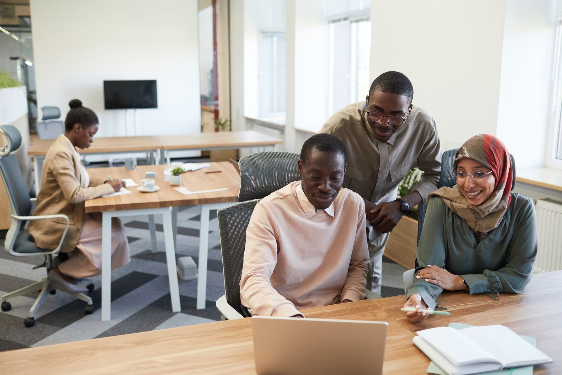 Diverse coworkers smiling together around a laptop