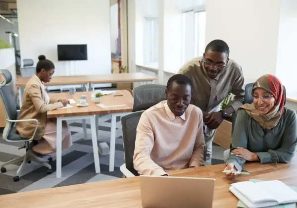 Diverse coworkers smiling together around a laptop