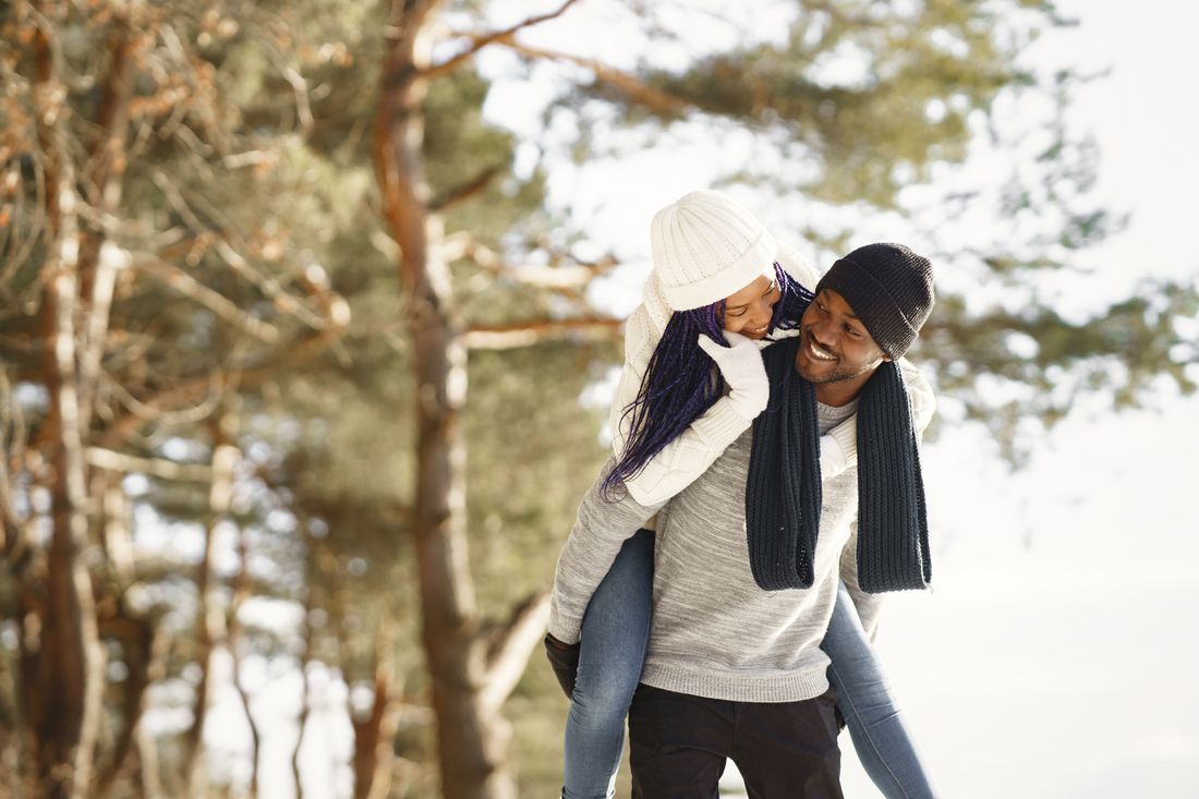 A husband giving his wife a piggyback ride on a winter walk